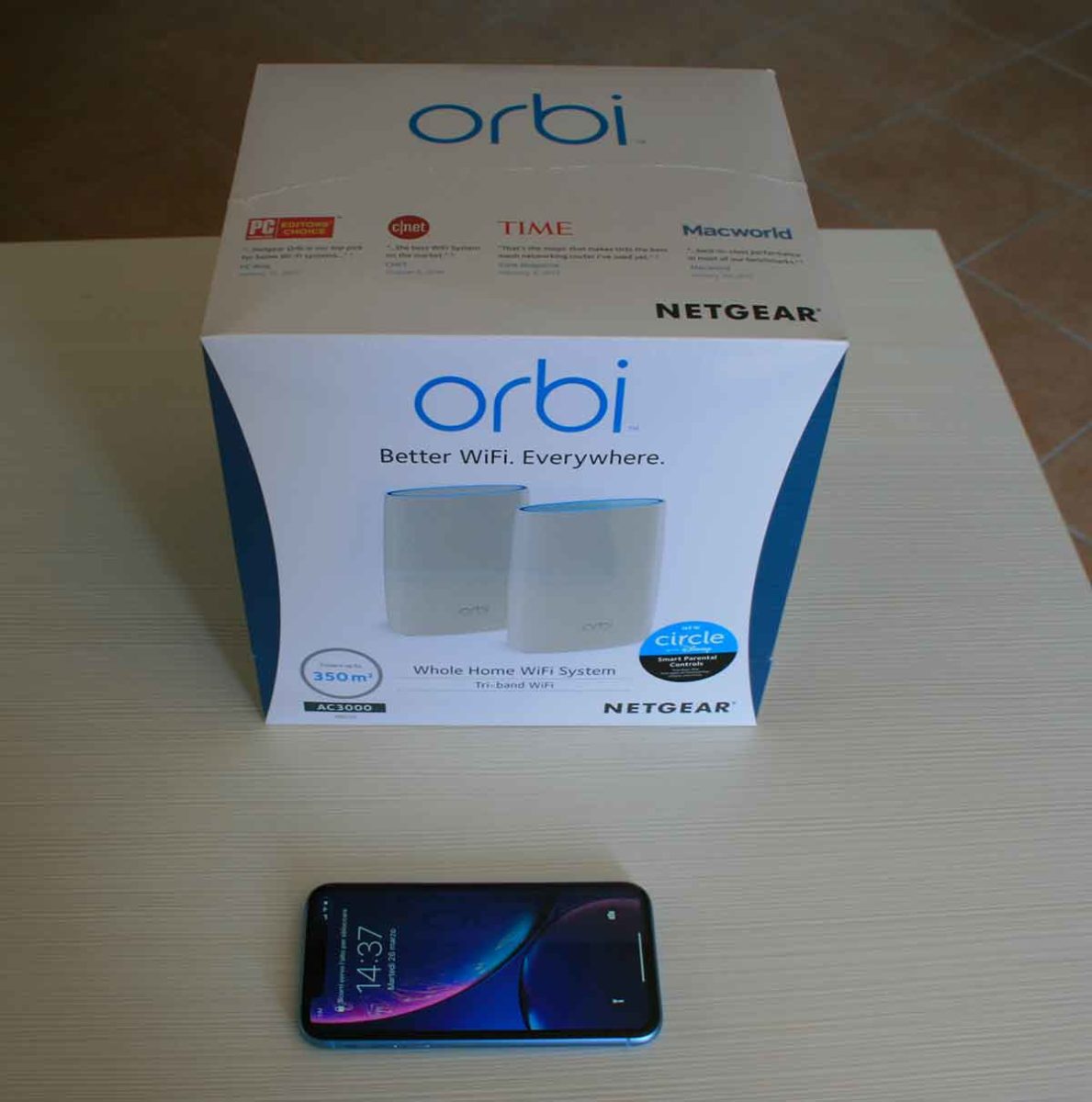 La confezione nella quale arriva il Sistema WiFi Orbi RBK50) vicino ad un iPhone XR