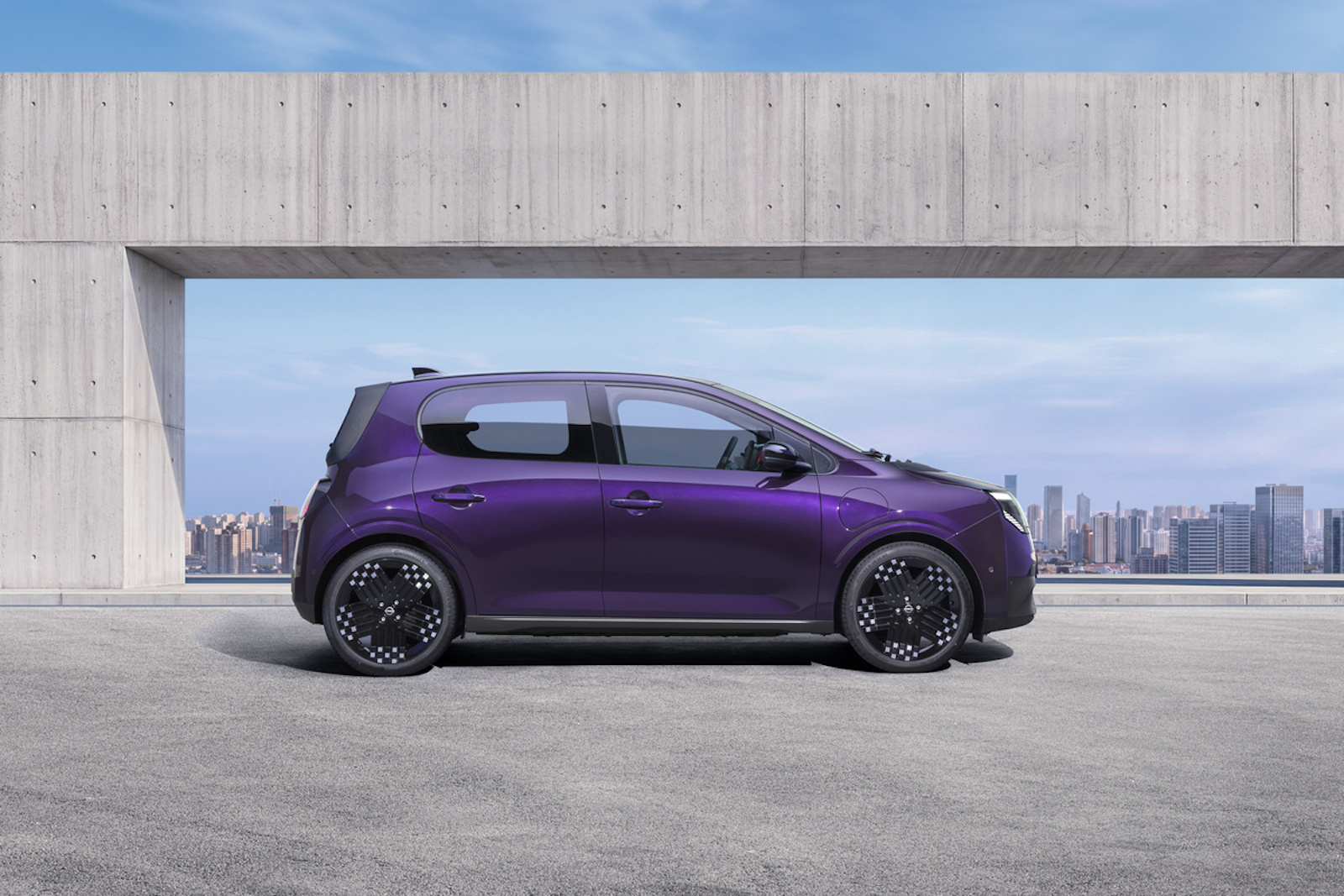 Nissan PIXO, la piccola elettrica da città nasce con Renault: 259 km di autonomia - macitynet.it Photograph showcasing a purple Nissan PIXO parked on a rooftop terrace. Side profile highlights aerodynamic shape, black alloy wheels concrete architectural frame, and city skyline backdrop.