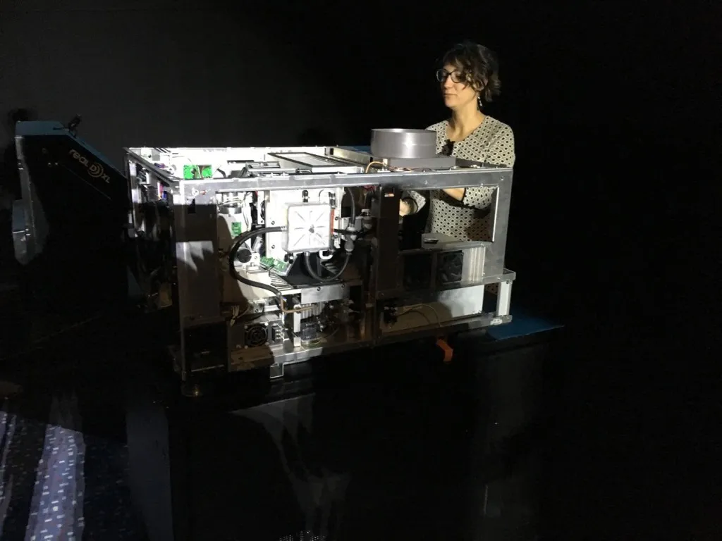 Alice Tentori, Country Manager Italia di RealD) davanti ad un proiettore 3D per display da 20 metri: sulla sinistra è visibile in modulo RealD® XL Cinema per il recupero della luce